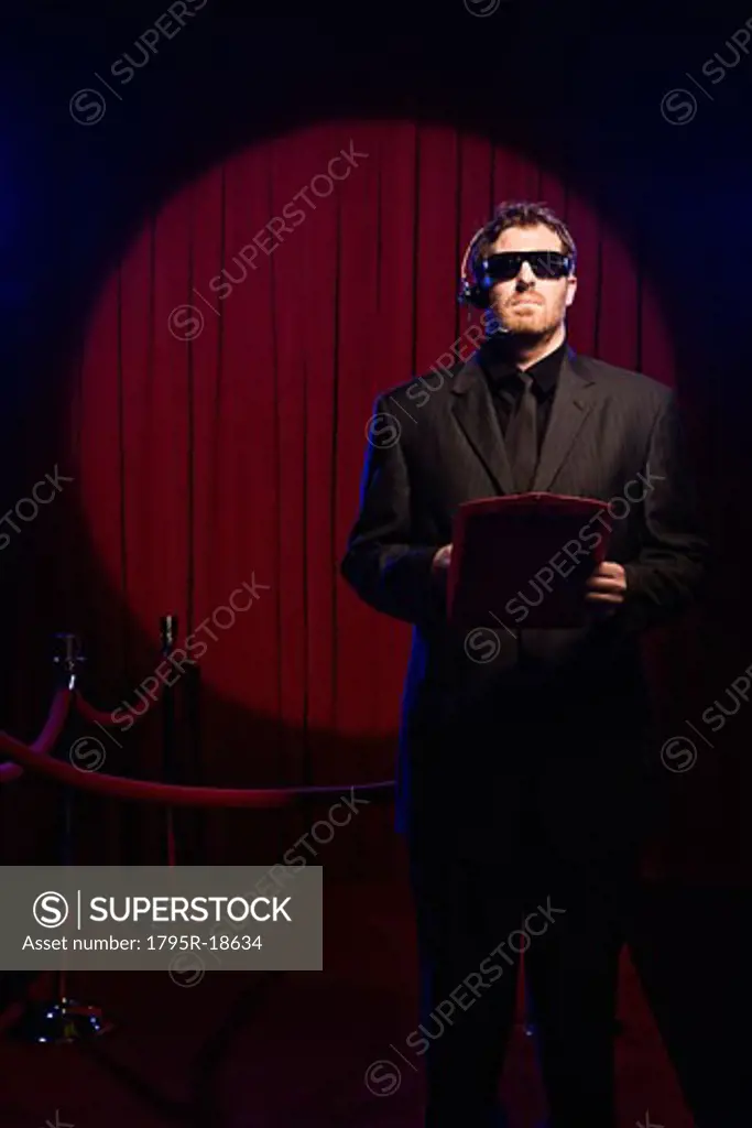 Bouncer with guest list standing near velvet rope