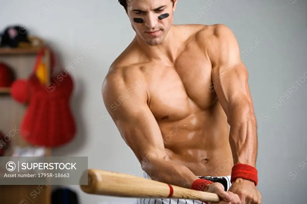 Baseball player with bare chest warming up with bat