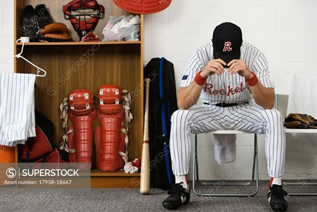 Baseball player sitting with head down in locker room