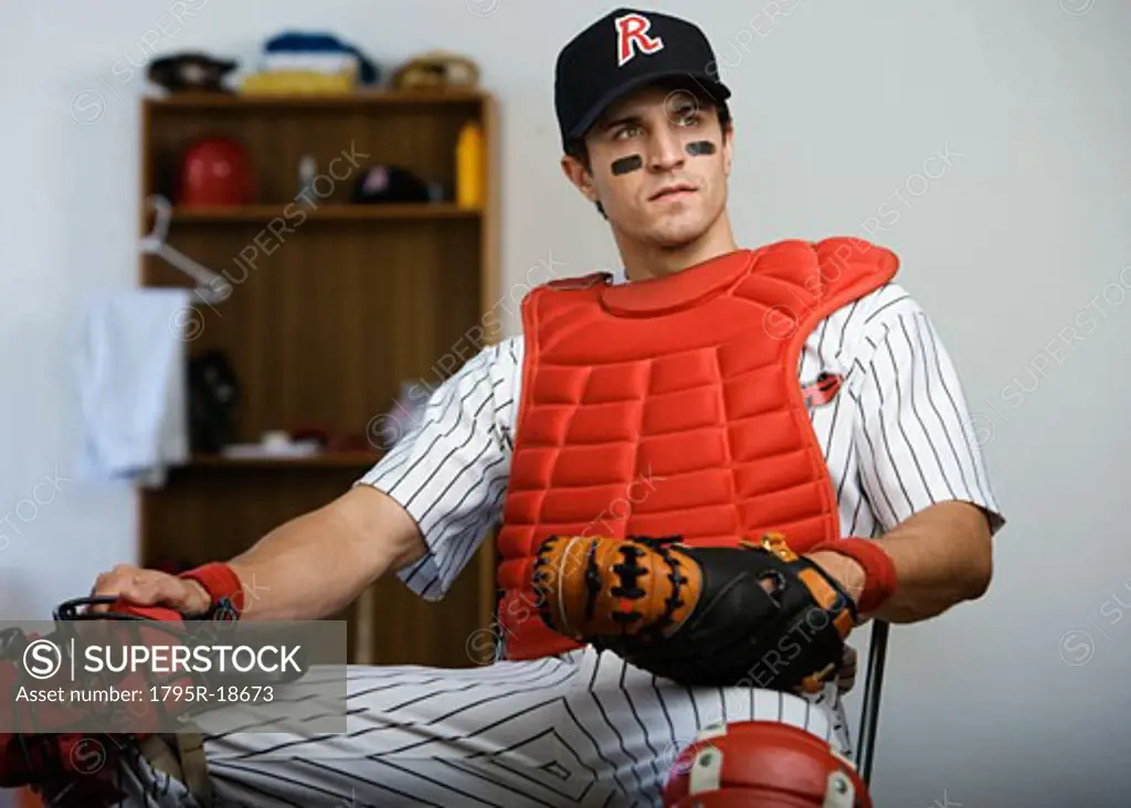 Baseball catcher sitting in locker room looking pensive