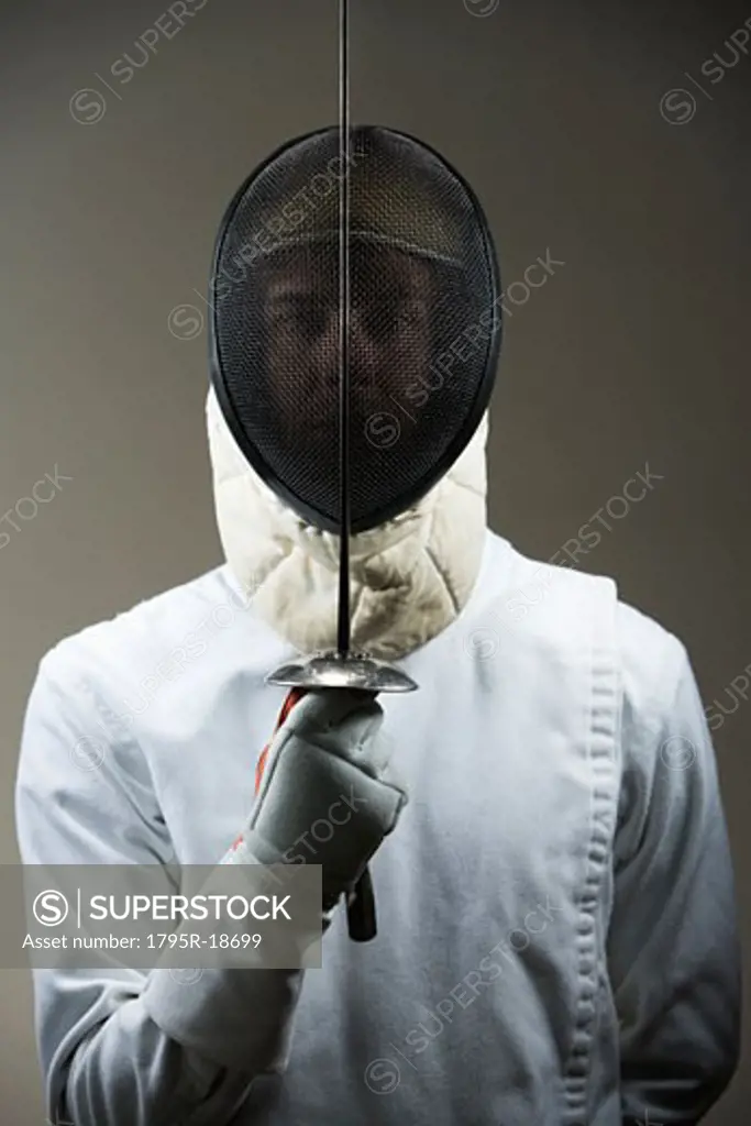 Portrait of fencer in uniform and mask holding fencing foil