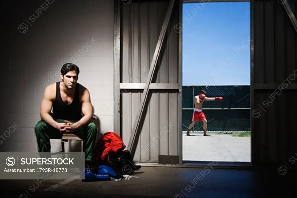 Man sitting on stool by doorway with boxer in background
