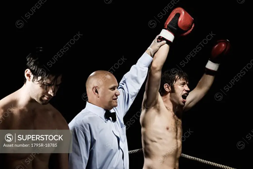 Referee standing between winning and losing boxers