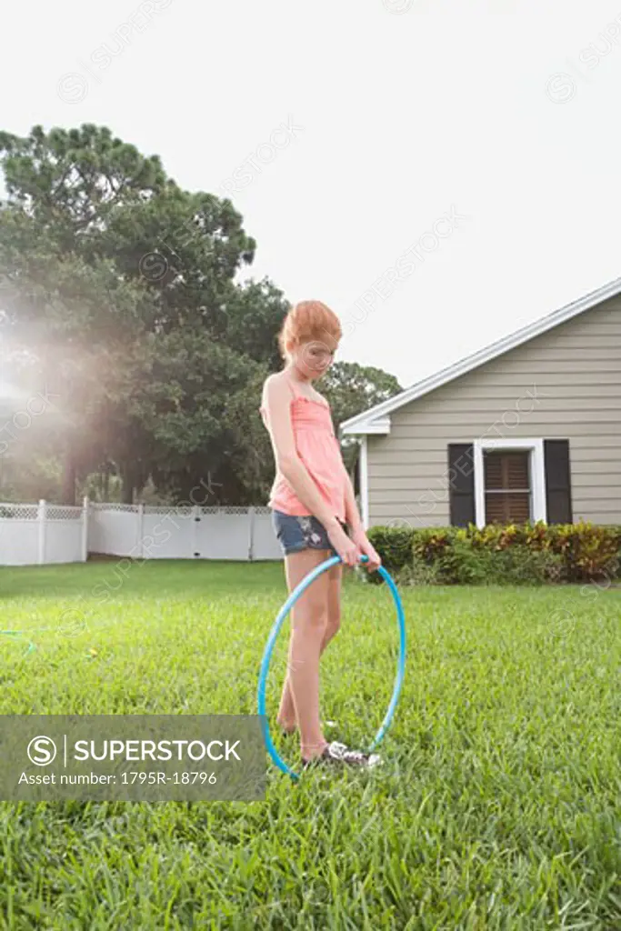 Girl standing in backyard with hula hoop