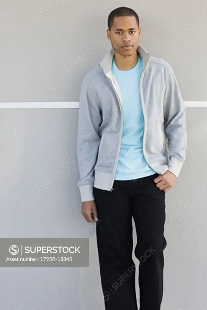 Portrait of young man leaning against wall