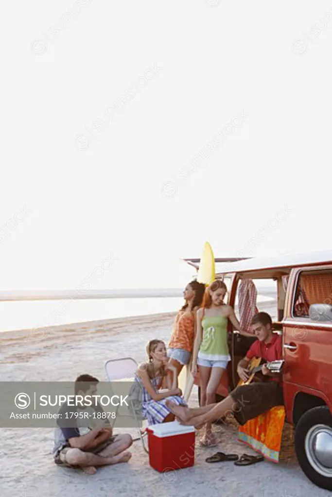 Friends lounging around van on beach