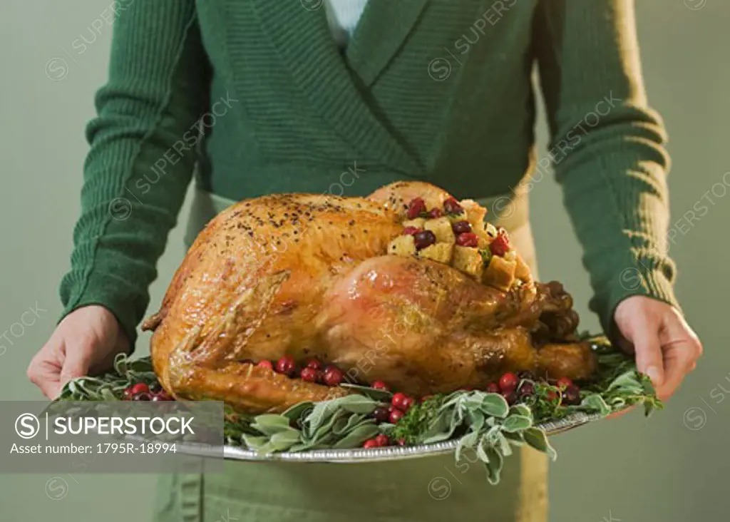 Man holding Thanksgiving turkey on decorated platter