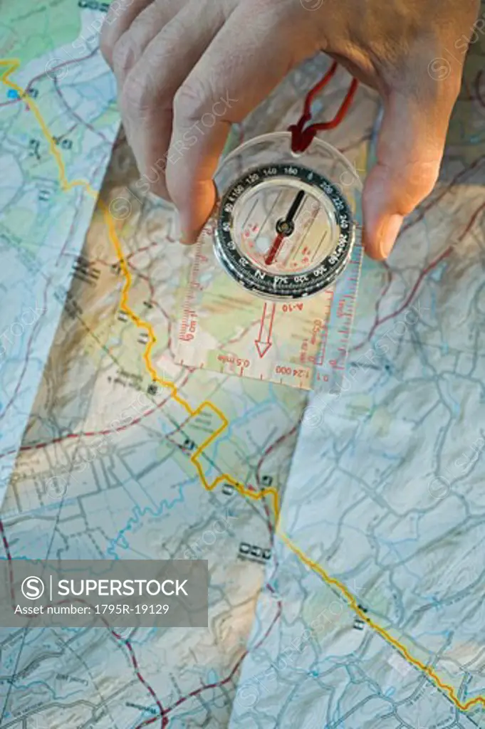 Man holding compass over map