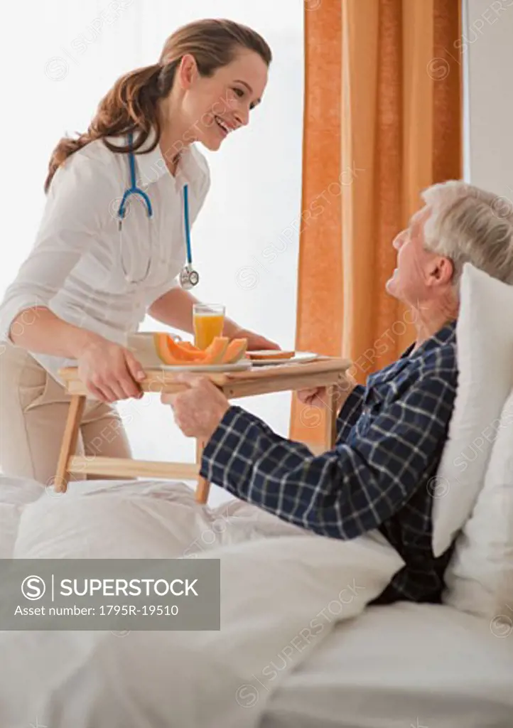 Nurse giving senior man breakfast
