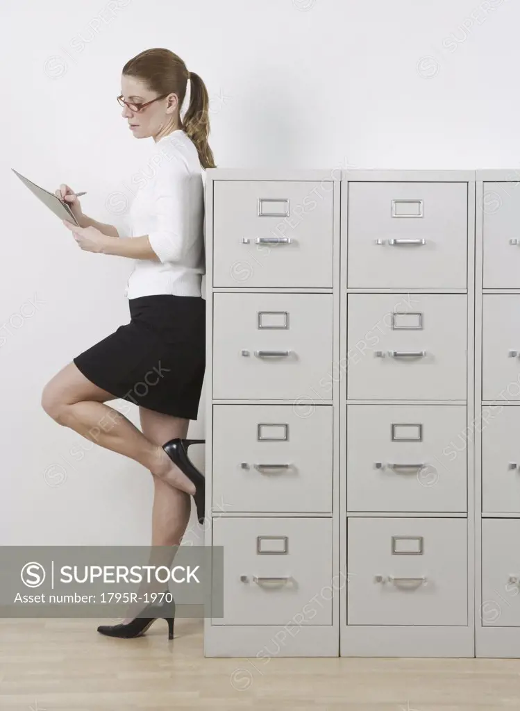 Redheaded woman leaning on file cabinets