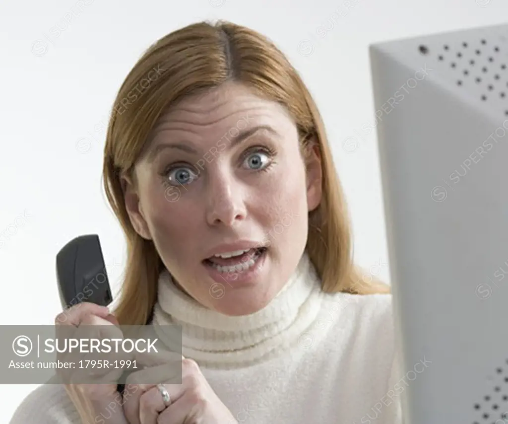 Annoyed woman with phone and computer