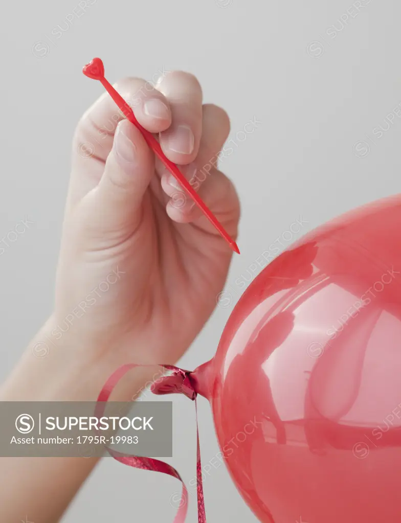 Woman popping red balloon