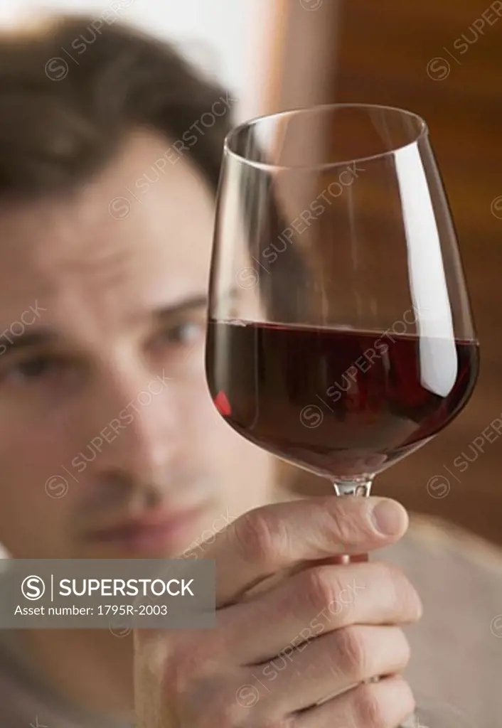 Man examining upheld glass of wine