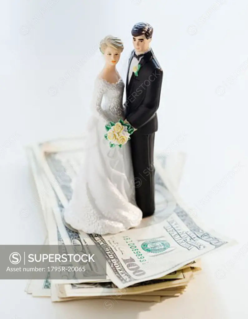 Wedding cake toppers on stack of cash