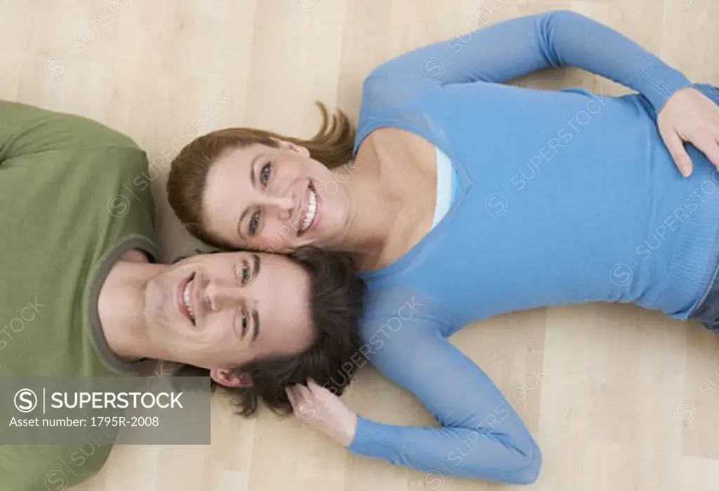 Smiling couple lying on wood floor