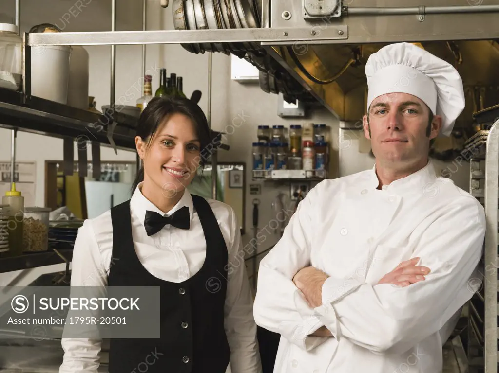 Chef and waitress posing in restaurant kitchen