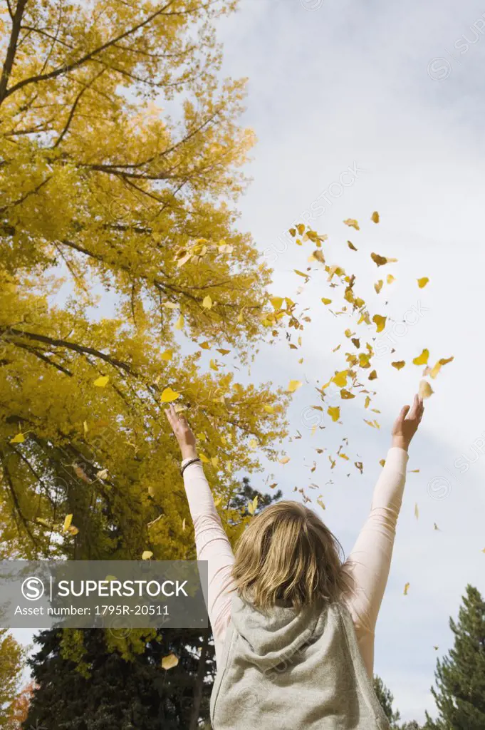 Woman throwing autumn leaves in air