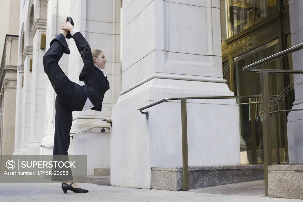 Businesswoman stretching on urban sidewalk