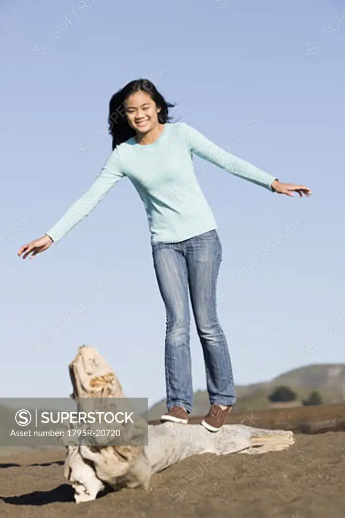 Teenage girl balancing on driftwood