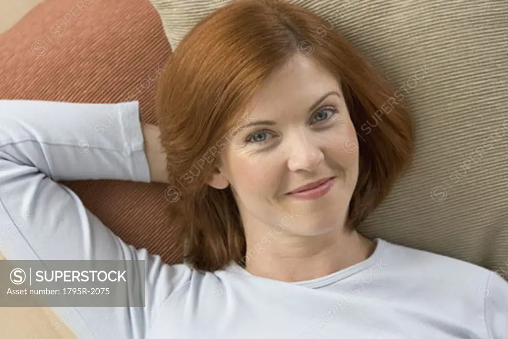 Smiling redheaded woman lying on pillows