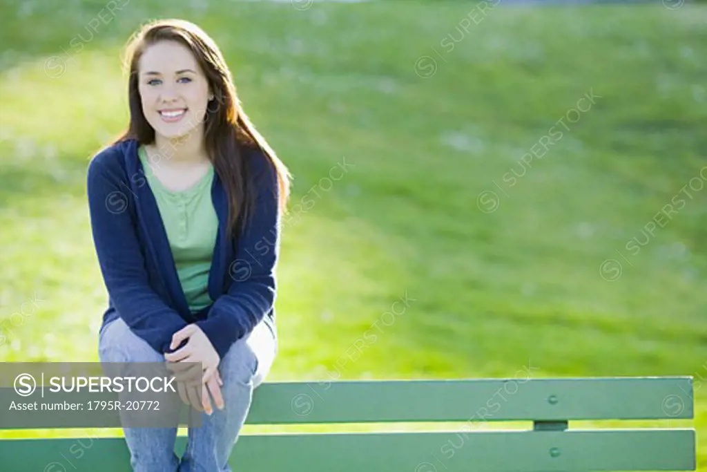 Teenage girl sitting on park bench