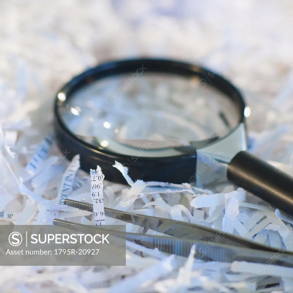 Confidential paperwork shredded with a magnifying glass and tweezers