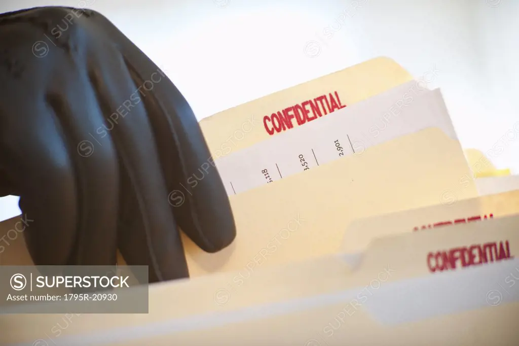 A gloved hand taking confidential files