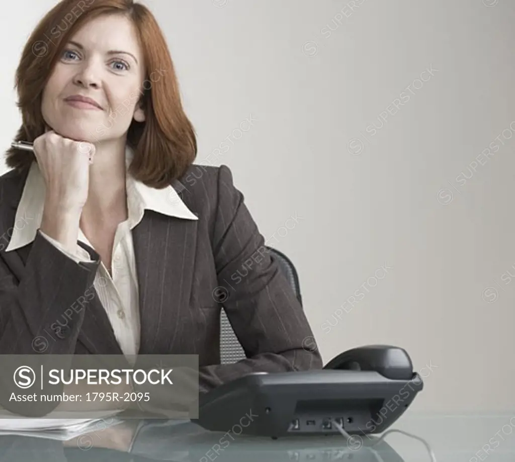 Attractive businesswoman with phone at desk