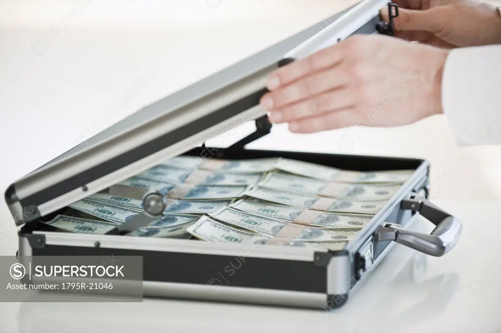 Hands closing a briefcase with money in it