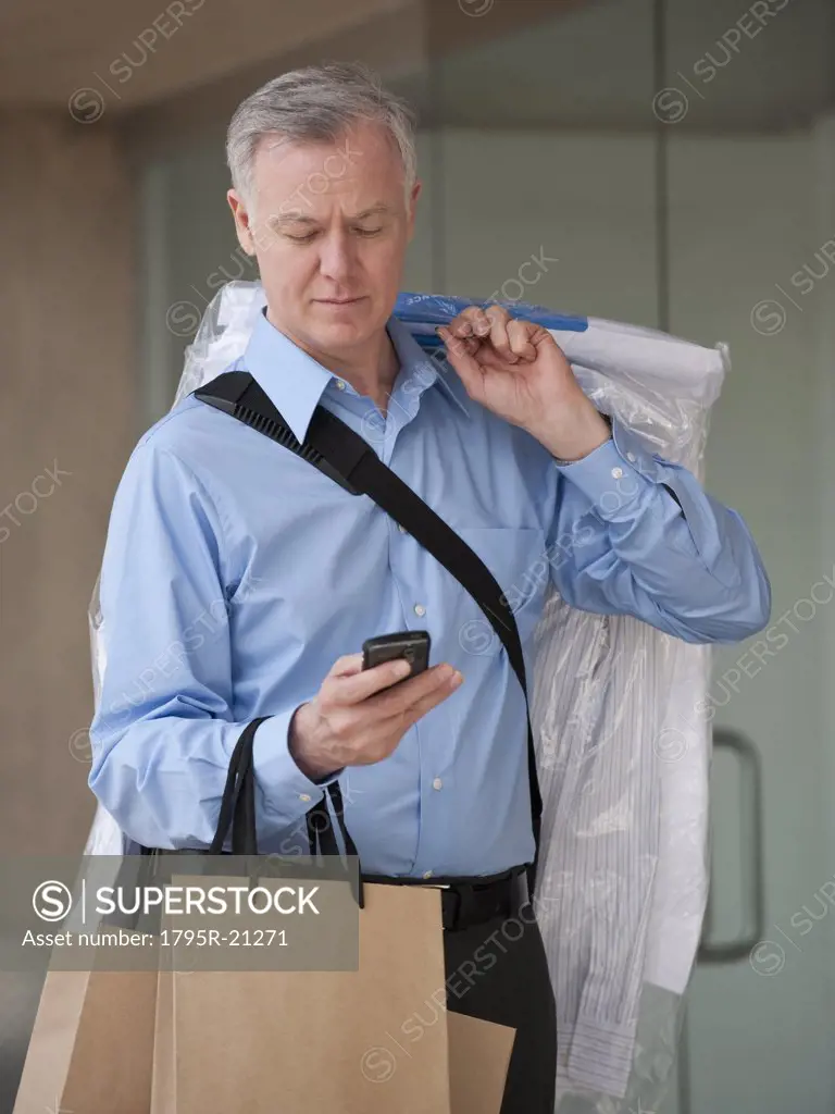 A man with dry cleaning and shopping bags