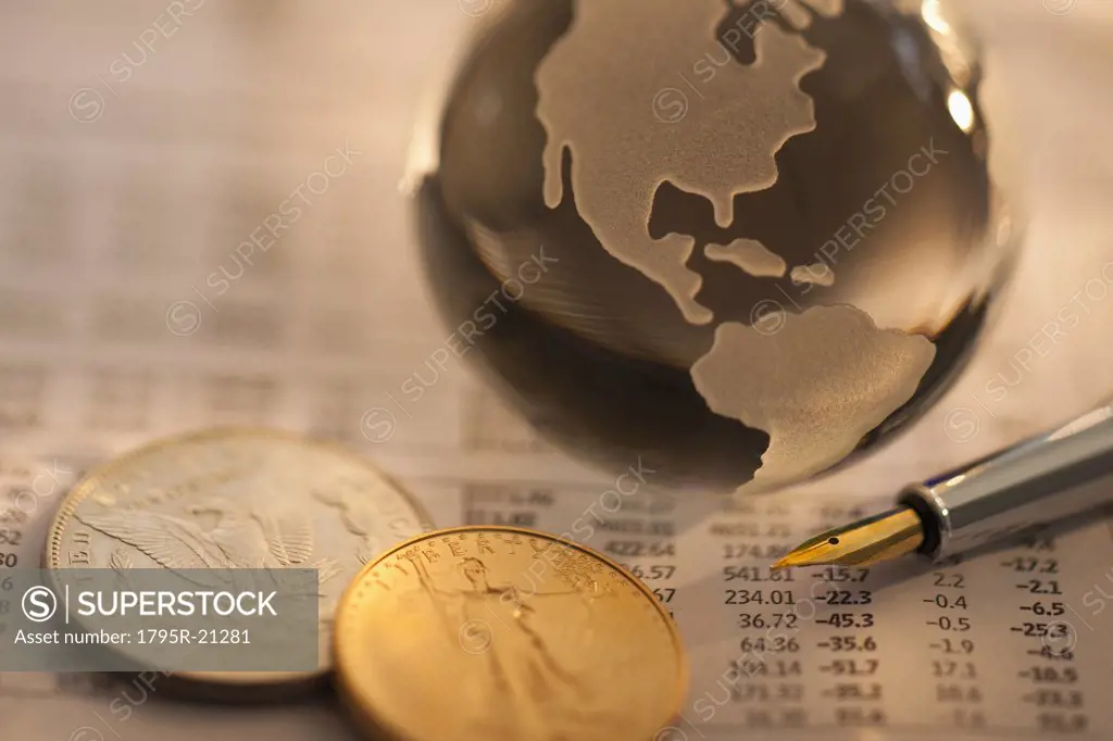 A globe on business papers with some coins