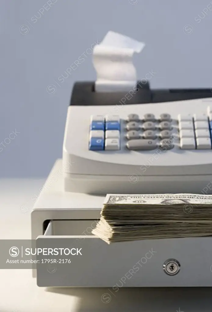 Cash register with pile of cash