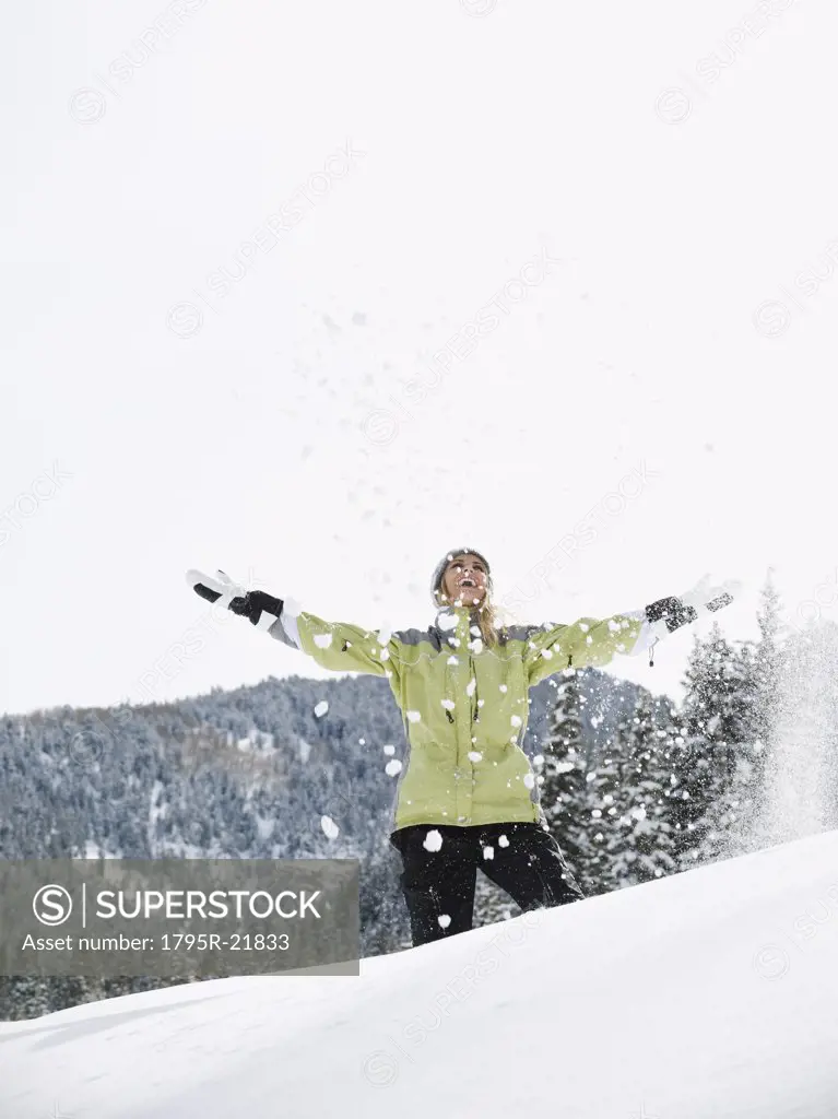A woman throwing snow up in air
