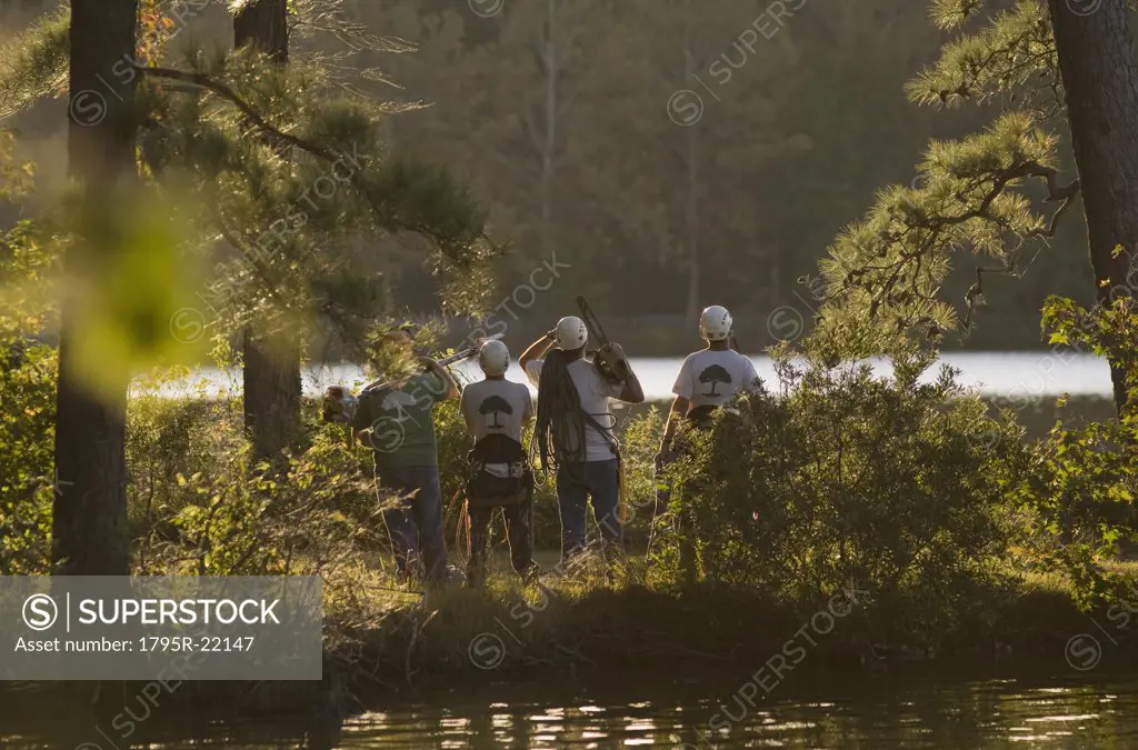 Four construction workers by a lake with tools