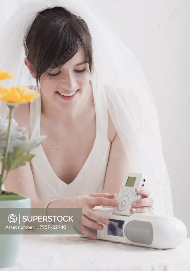 Bride holding speakers of stereo, studio shot