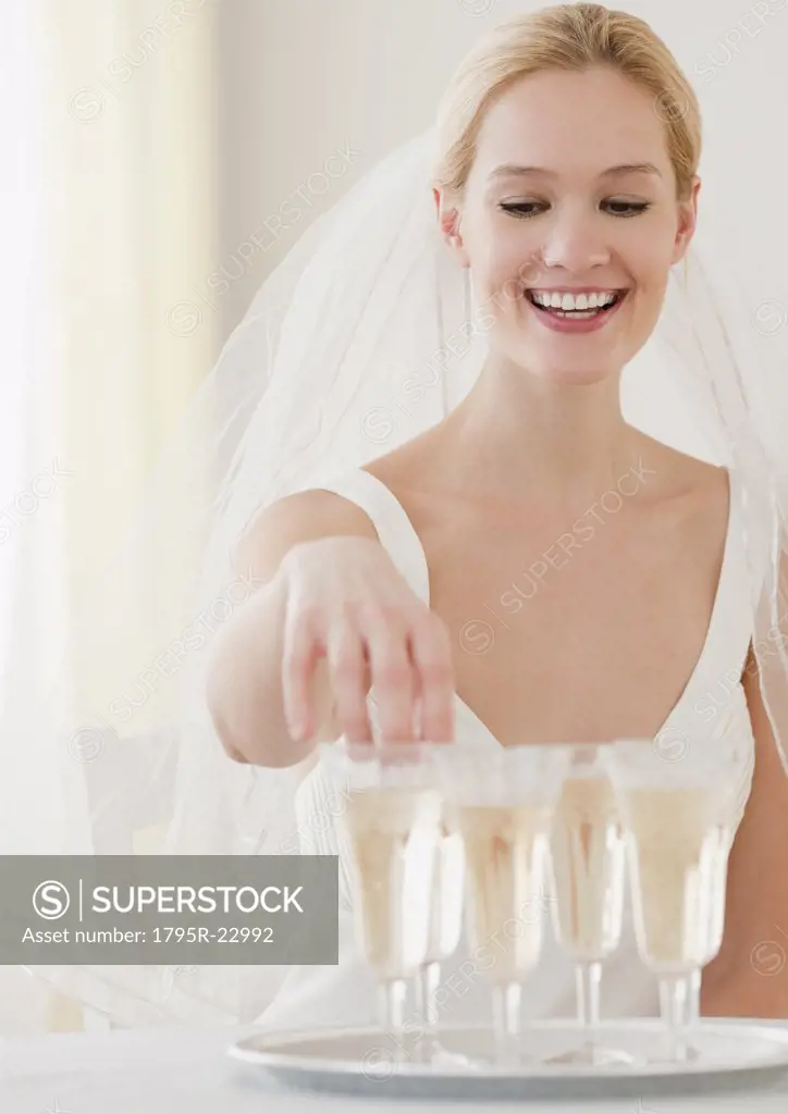 Young bride reaching for glass of champagne