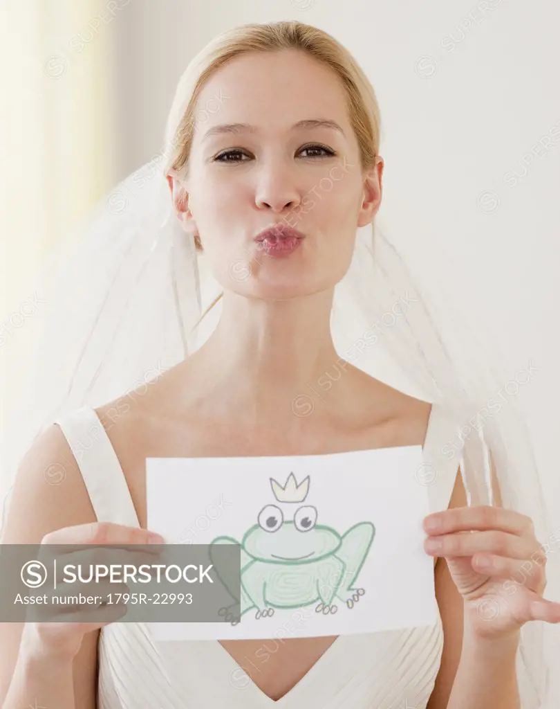 Portrait of young bride blowing kiss and holding drawing of frog prince