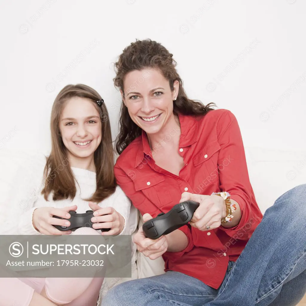 Mother and daughter (10-12 years) playing video game, portrait