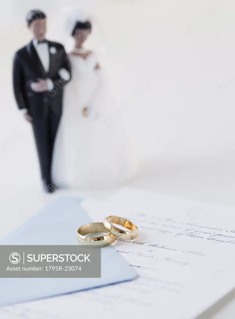 Wedding rings by bride and groom cake toppers on marriage certificate