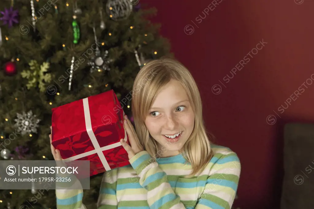 Teenage girl (10-12) shaking Christmas gift