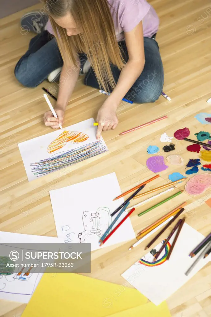 Girl (10-12) sitting on floor and drawing pictures