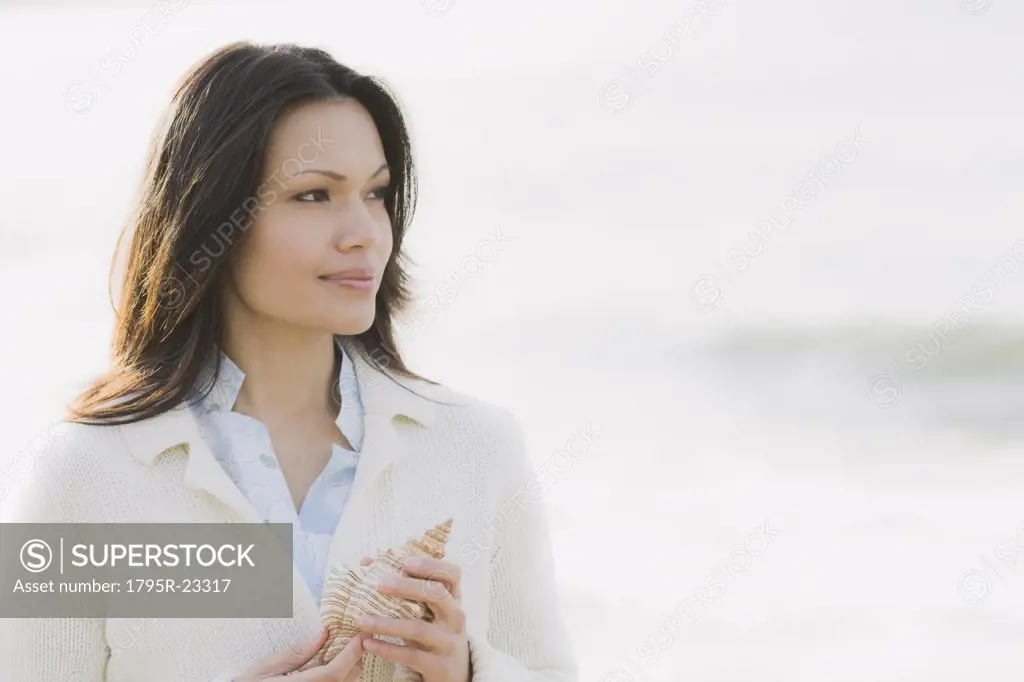 Woman holding shell by sea