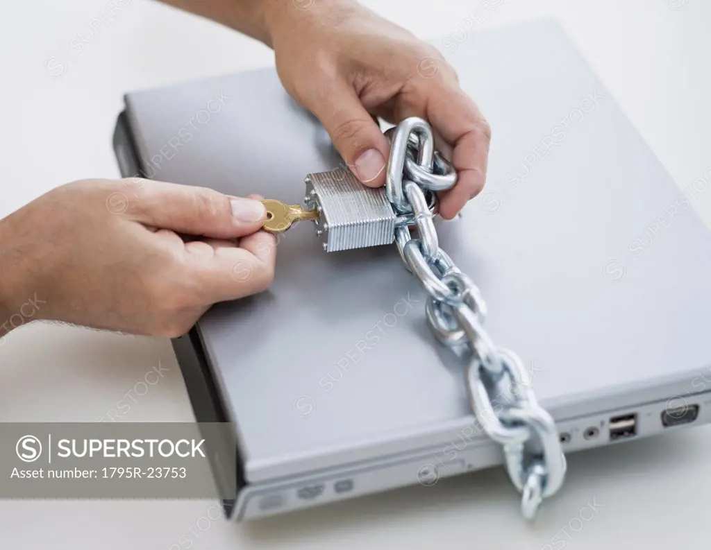 Hands placing lock and chain on computer