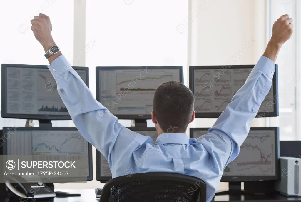 Male trader raising arms in success