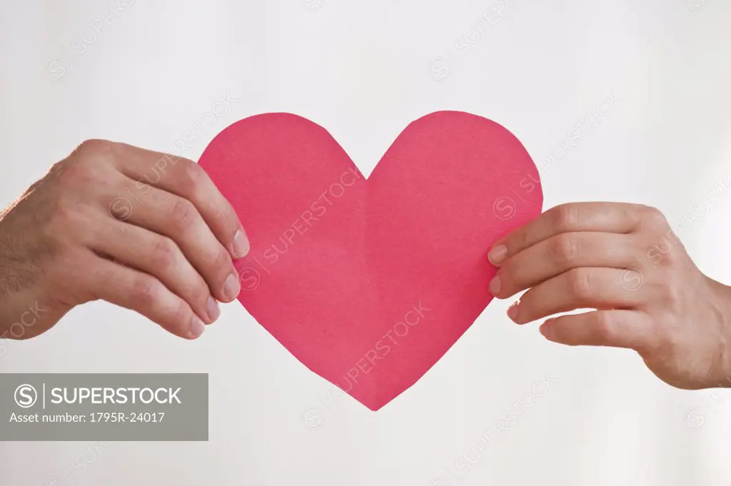 Two hands holding paper heart