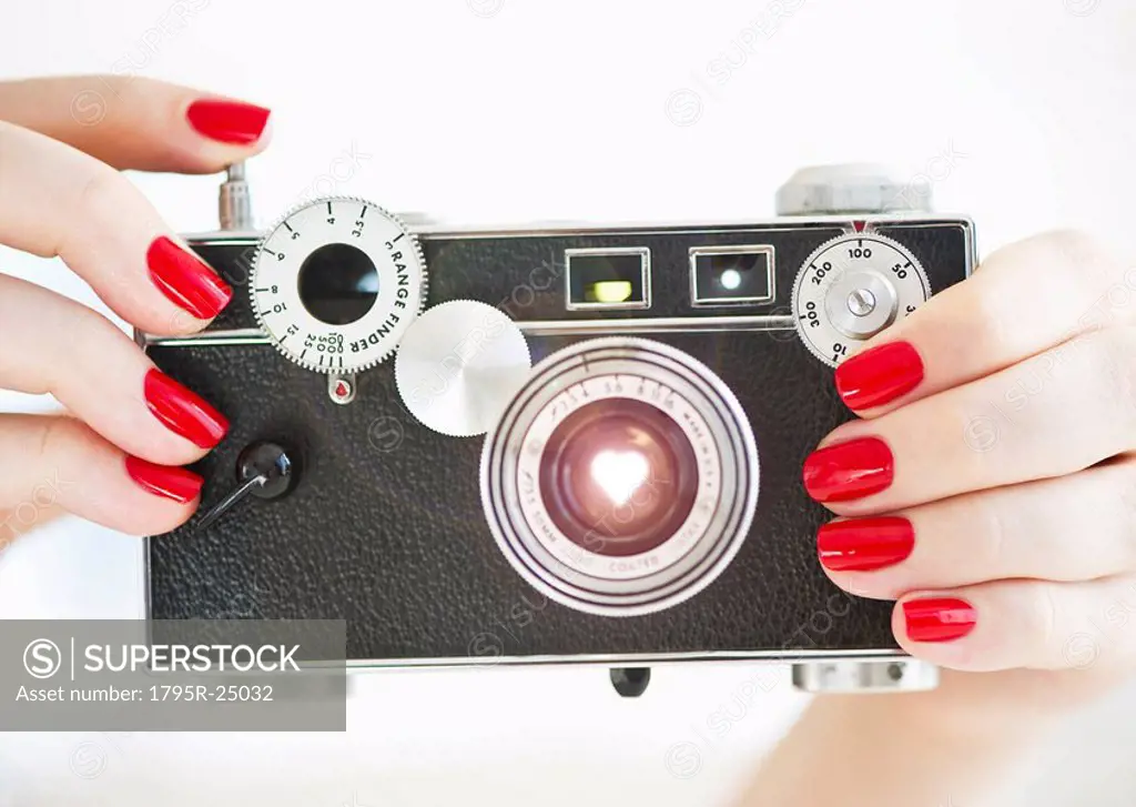 Antique camera being held by woman wearing red nail polish