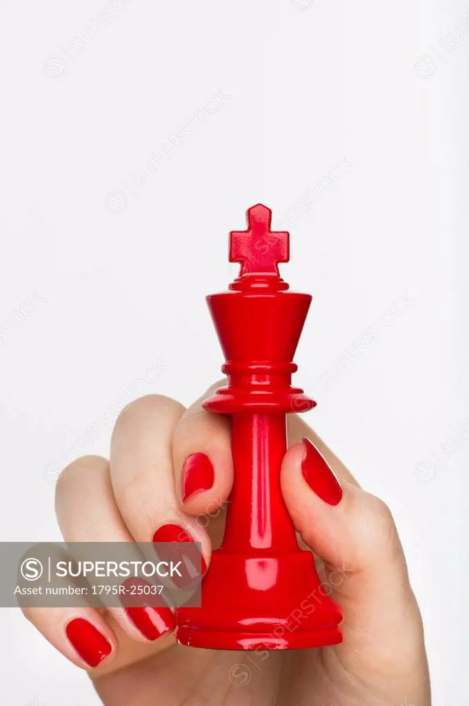Hand holding red king chess piece