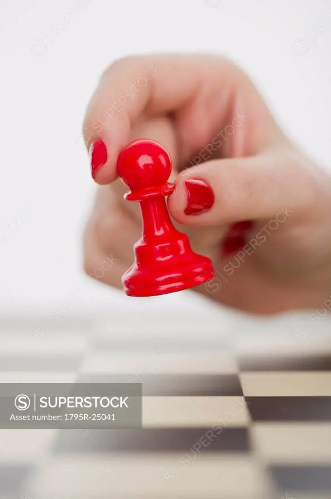 Hand holding red pawn chess piece