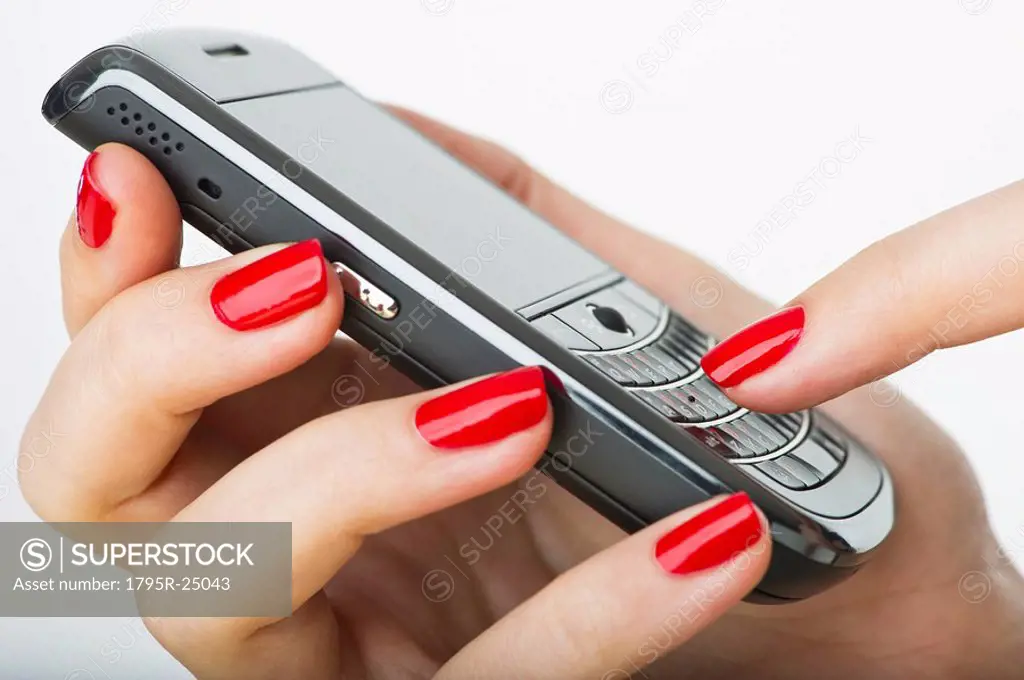 Woman wearing red nail polish texting on cell phone