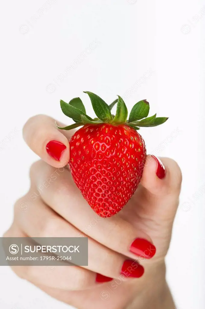 Hand holding red strawberry